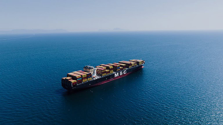 Sea Freight to Sarawak - An aerial shot of a loaded container ship sailing near Naples, Italy under clear blue skies.