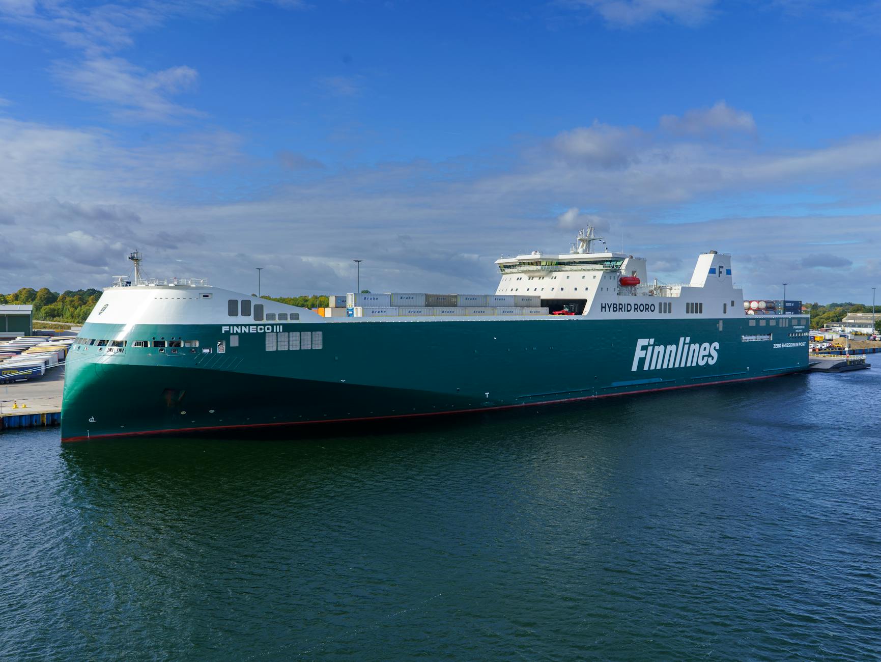 Hybrid RoRo ship 'Finneco III' docked at a bustling port under clear skies.