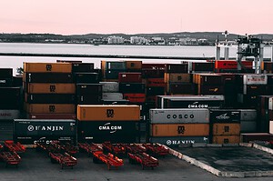 A bustling container yard at a seaport with shipping containers stacked and ready for transport at twilight.