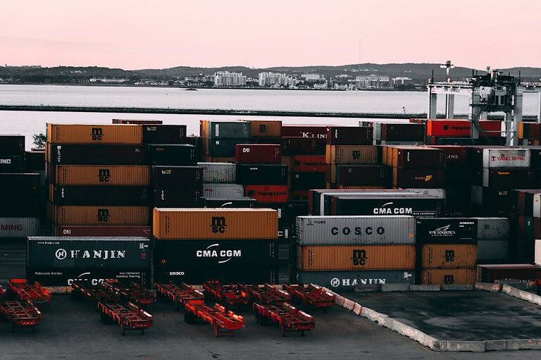 A bustling container yard at a seaport with shipping containers stacked and ready for transport at twilight.